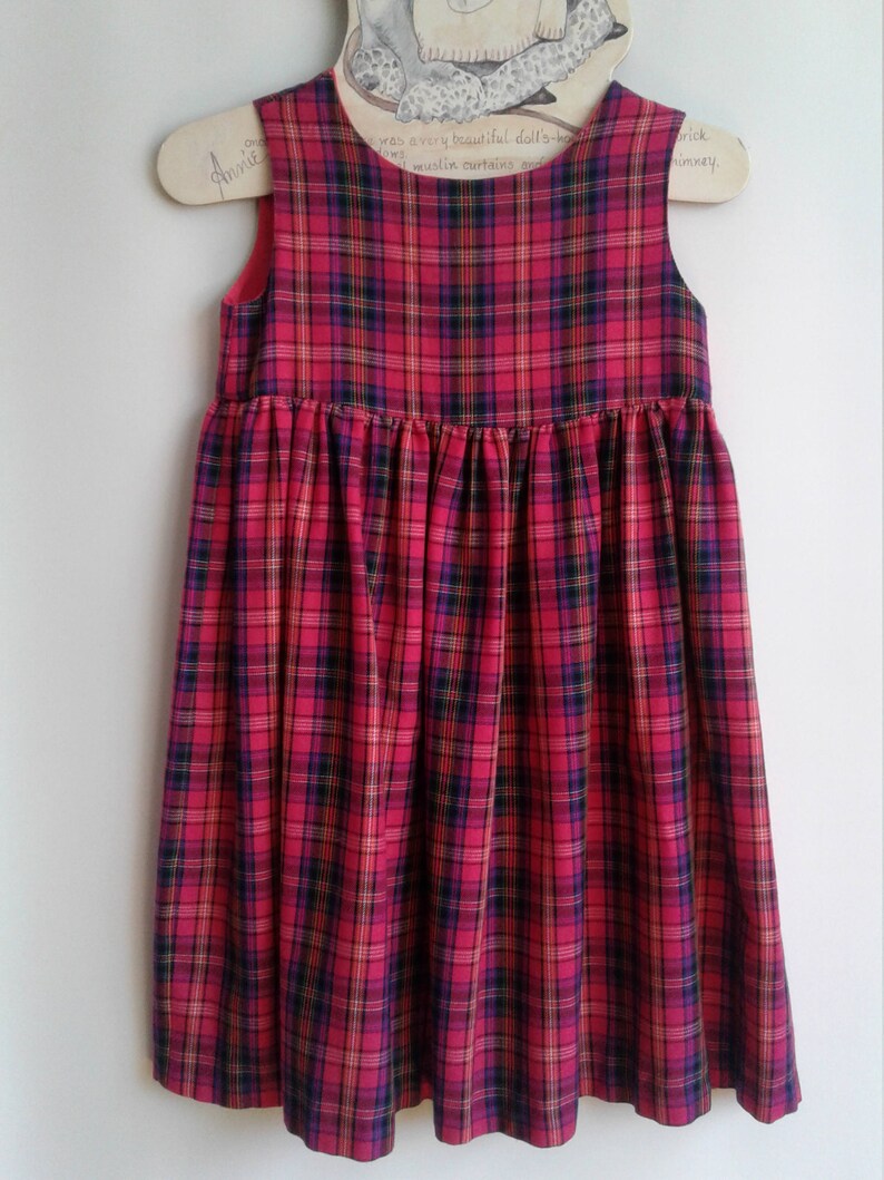 Puede incluir: Un vestido sin mangas de cuadros rojos, negros y amarillos con falda fruncida.