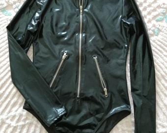 May include: Black long-sleeved bodysuit with a zipper up the front and two zippered pockets on the sides. The bodysuit is made of a shiny, wet-look material.