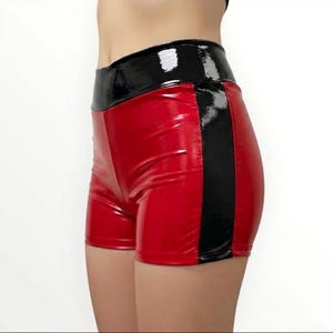 Op de afbeelding: Rood en zwart hoog getailleerde shorts. De shorts zijn gemaakt van een glanzend, lakleerachtig materiaal. De tailleband en een verticale streep zijn zwart. De rest van de shorts is rood.