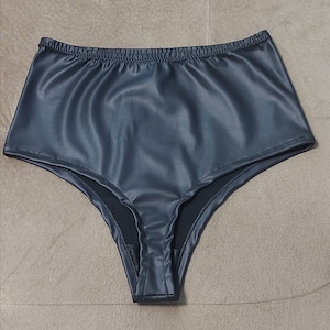 Puede incluir: Ropa interior de talle alto confeccionada en material de piel sint&eacute;tica de color gris carb&oacute;n oscuro. La prenda presenta un acabado mate y liso con una cintura el&aacute;stica fruncida y aberturas de pierna cosidas, ofreciendo una silueta estructurada.
