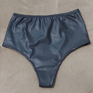Puede incluir: Ropa interior de talle alto en color gris carb&oacute;n oscuro con un acabado liso y semibrillante. La prenda cuenta con una cintura el&aacute;stica y aberturas para las piernas cosidas, confeccionada en un material flexible con aspecto de cuero.