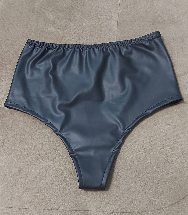 Puede incluir: Ropa interior de talle alto en color gris carb&oacute;n oscuro con un acabado liso y semibrillante. La prenda cuenta con una cintura el&aacute;stica y aberturas para las piernas cosidas, confeccionada en un material flexible con aspecto de cuero.