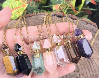 May include: A collection of gemstone pendant necklaces in various colors, including tiger's eye, black onyx, green fluorite, rose quartz, clear quartz, smoky quartz, and amethyst. Each pendant is a unique shape and hangs from a gold chain. The text "Forbeads" is visible.