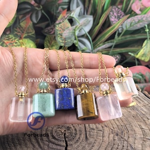 Puede incluir: Una colección de collares con colgantes de piedras preciosas en varios colores, incluyendo transparente, verde, azul, marrón y rosa. Cada collar presenta un pequeño colgante rectangular en forma de botella con una cadena y tapa doradas. El nombre de la tienda Etsy "Forbeads" es visible.