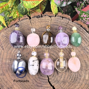 Pode incluir: Dez pequenos pingentes em forma de frasco de perfume feitos de várias pedras preciosas polidas, incluindo ametista, quartzo rosa, olho de tigre e quartzo transparente. Cada pingente possui uma tampa de metal dourado e uma pequena argola.