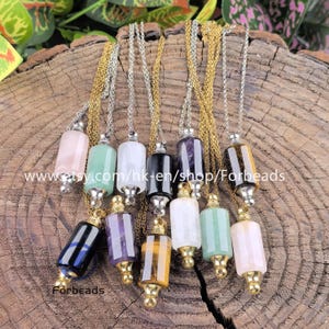 Puede incluir: Una colección de collares con péndulos de cristal en varios colores, como rosa, verde, blanco, negro y morado. Cada péndulo cuelga de una cadena plateada o dorada. La imagen incluye el texto "www.etsy.com/hk-en/shop/Forbeads" y "Forbeads".