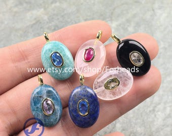 May include: Six oval-shaped pendants featuring smooth gemstones in turquoise, pink, black, blue, and clear, each set with a smaller oval faceted stone in a gold-tone bezel. The text www.etsy.com/shop/Forbeads and Forbeads is visible on the image.