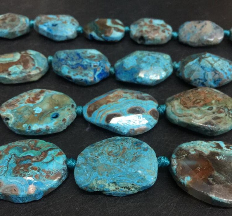 May include: A strand of blue and brown agate gemstone beads. The beads are oval shaped and have a natural, polished finish.