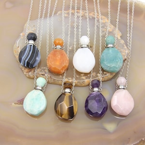 Może przedstawiać: Osiem srebrnych naszyjników z kamiennymi butelkami w formie zawieszek. Zawieszki wykonane są z agatu, karneolu, białego, awenturynu, tygrysiego oka, ametystu i różowego kwarcu.