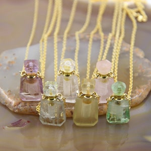May include: Five gold chain necklaces with crystal perfume bottle pendants. The bottles are in various colors, including pink, green, and clear.