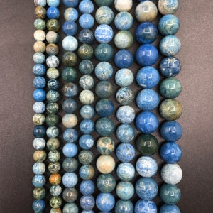 May include: A strand of blue and green gemstone beads. The beads are round and have a mottled, textured surface.