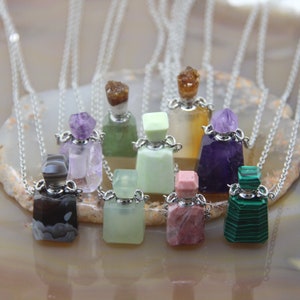 Może przedstawiać: Kolekcja dziesięciu naszyjników z buteleczkami perfum z kamieni szlachetnych. Naszyjniki prezentują różne kamienie szlachetne, w tym ametyst, agat, malachit i kwarc różowy. Każda buteleczka ma srebrny korek i jest przymocowana do srebrnego łańcuszka.