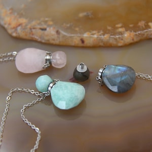 Puede incluir: Tres collares con colgantes de piedras preciosas y cadenas de plata. Los colgantes tienen forma de botella y están hechos de cuarzo rosa, aventurina verde y labradorita.