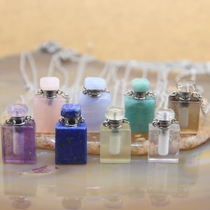 Puede incluir: Un conjunto de ocho pequeños frascos de perfume cuadrados de cristal con tapones y cadenas plateadas. Los frascos están hechos de varias piedras semipreciosas, incluyendo amatista, cuarzo rosa, lapislázuli, calcedonia azul, aventurina verde, cuarzo transparente y cuarzo ahumado.