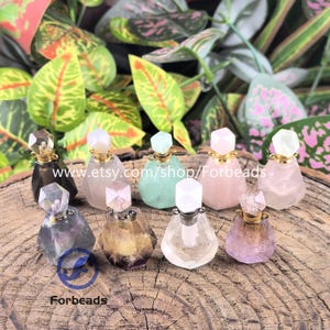 May include: A collection of nine small, faceted gemstone perfume bottles with gold-tone metal caps. Each bottle features a unique translucent or opaque mineral stone body in various colors including clear, pink, green, purple, and smoky gray.