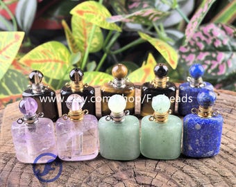 Puede incluir: Una colección de pequeños frascos de perfume cuadrados con tapones de piedras preciosas. Los frascos son transparentes y los tapones son de amatista, cuarzo, jade y lapislázuli. Los frascos están dispuestos sobre una superficie de madera, con el texto "Forbeads".