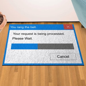 May include: A blue and white doormat with a computer error message that says "You rang the bell. Your request is being processed. Please Wait."  The message has a progress bar and a "Cancel" button.