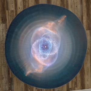 May include: A close-up of a nebula with a swirling, blue and pink pattern. The nebula is surrounded by a dark blue background.