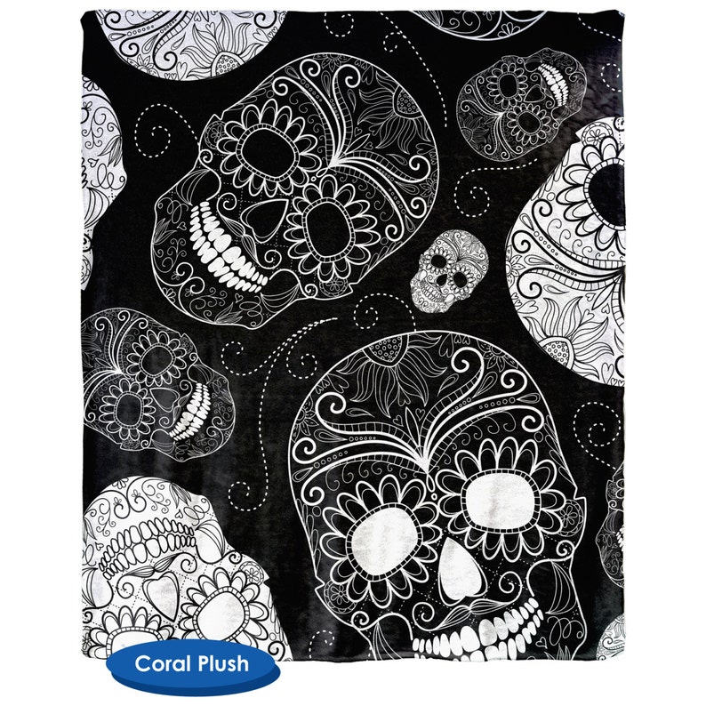 May include: Black and white patterned throw blanket with a repeating design of sugar skulls. The skulls are intricately detailed with floral patterns and swirls.