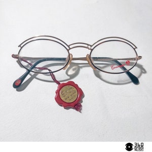 May include: Gold-rimmed round eyeglasses with a red wax seal tag that reads "Casanueva Sunglasses 24K Gold 925/1000".