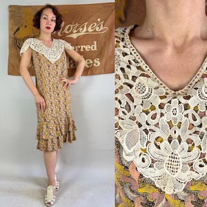 Pode incluir: Um vestido vintage com gola de renda creme e mangas curtas. O vestido tem decote em V e um padrão em tons de amarelo, castanho e rosa. A saia tem bainha com babados e o vestido é até ao joelho.