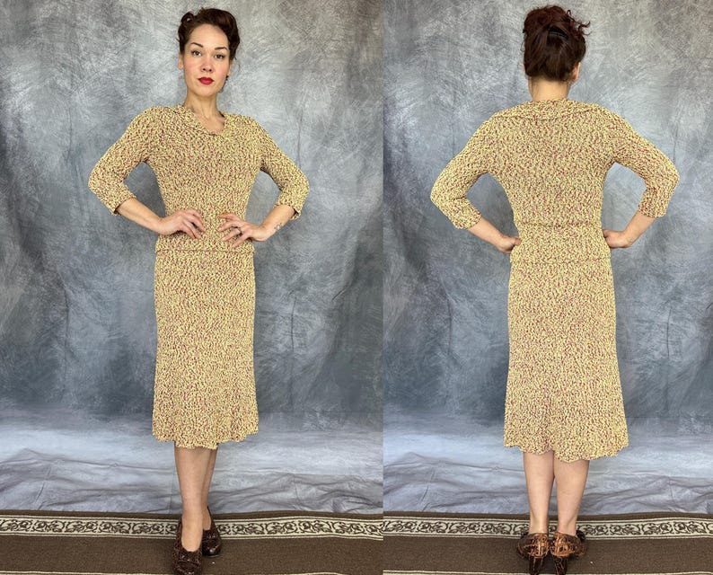 May include: A vintage two-piece dress set in a speckled pattern of tan and red. The set includes a long-sleeved top with a V-neck and a knee-length skirt. The outfit is worn by a person in a studio setting.