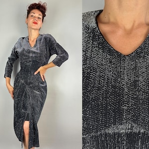 May include: A vintage black dress with a V-neck and three-quarter sleeves. The dress features a fitted bodice and a skirt with a front slit. The fabric has a subtle metallic sheen, adding glamour to the classic silhouette.