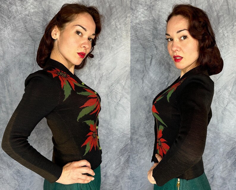 May include: A black knit cardigan with a poinsettia design in red and green. The long-sleeved jacket has a button-up front and is worn with a green skirt. The cardigan is a vintage style, perfect for the holiday season.