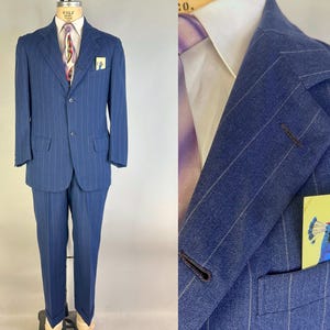 Puede incluir: Un traje azul de rayas diplom&aacute;ticas que incluye una chaqueta de dos botones con solapas de muesca y pantalones a juego. La chaqueta se combina con una camisa blanca, una corbata estampada y un pa&ntilde;uelo con un pavo real con sombrero rojo.