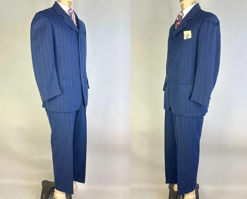 Puede incluir: Un traje azul oscuro con rayas diplom&aacute;ticas que incluye una chaqueta de tres botones con solapas de muesca y pantalones a juego. La chaqueta cuenta con un bolsillo en el pecho con una etiqueta rectangular, dos bolsillos con solapa, camisa y corbata.