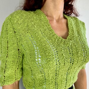 May include: A lime green knit top with a V-neck and short sleeves. The knit pattern features openwork details and a textured appearance. The top is made of a soft, lightweight material, perfect for warmer weather.