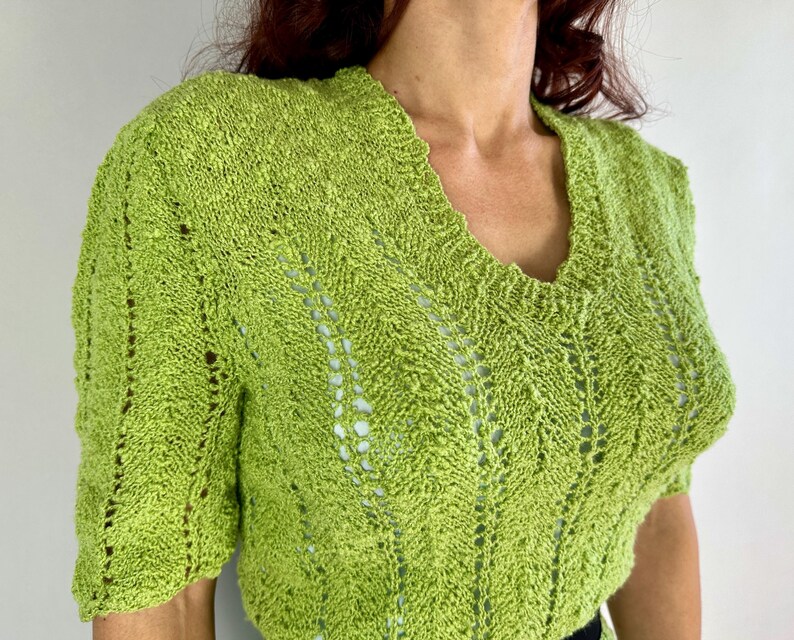 May include: A lime green knit top with a V-neck and short sleeves. The knit pattern features openwork details and a textured appearance. The top is made of a soft, lightweight material, perfect for warmer weather.