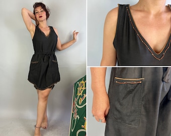 May include: A black sleeveless dress with a V-neckline and a brown trim. The dress has a tie belt and two pockets on the front.