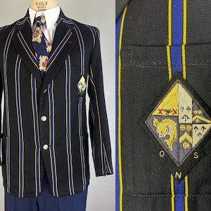 May include: Black blazer with vertical yellow and blue stripes. The blazer has a crest on the chest pocket and three silver buttons. A patterned tie and white collared shirt are visible underneath.
