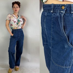 Könnte beinhalten: Dunkelblaue Jeanshose mit hohem Bund und großen Vordertaschen. Die Hose hat einen Knopfverschluss und weiße Nahtdetails. Das Model trägt ein Oberteil mit floralem Muster.
