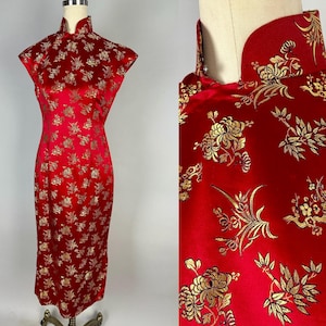 Puede incluir: Vestido rojo con mangas cortas y cuello mandarín. El vestido está hecho de una tela brillante y presenta un estampado floral dorado. El vestido se exhibe en un maniquí.