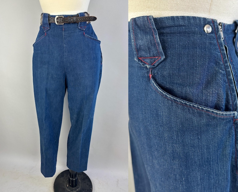 May include: High-waisted dark blue denim trousers featuring a front zipper closure, a silver-tone metal button, and distinctive red contrast stitching along the pockets and waistband. A thin dark brown textured leather belt is threaded through loops.