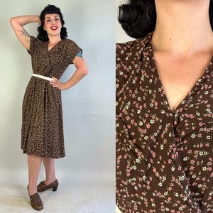 May include: A vintage brown dress with a small white and tan pattern. The dress has short sleeves, a V-neck, and a white belt. The dress is knee-length and paired with brown shoes.