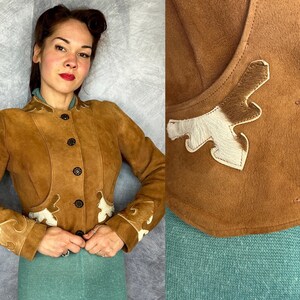 Peut inclure: Une veste en daim beige dotée d'une fermeture boutonnée, de manches longues et d'applications décoratives en cuir de vachette blanc et marron sur les poignets et les panneaux avant inférieurs. Elle possède un col haut et des boutons marron foncé.
