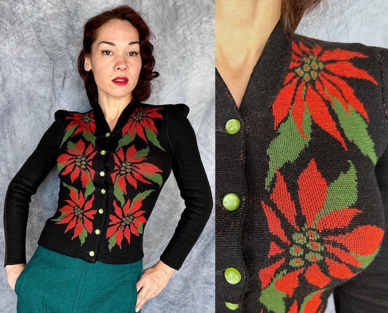 May include: Black cardigan sweater with a poinsettia floral design in red and green. The long-sleeved sweater has a V-neck, shoulder pads, and gold-colored buttons. The woman is wearing a teal green skirt.