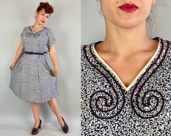 May include: A blue and white floral print dress with a white collar and a dark blue trim. The dress has a fitted bodice and a full skirt.