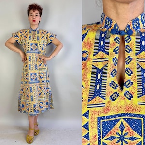 以下が含まれることがあります： マンダリンカラーとキーホールネックラインのイエローとブルーのパターンミディドレス。ドレスは赤のアクセントのある幾何学模様です。