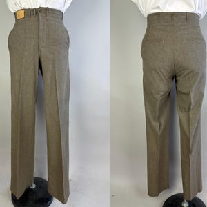 Op de afbeelding: Broek met hoge taille in een effen bruine kleur, voorzien van een rechte pijp, een knoop- en ritssluiting, riemlussen en een klein rechthoekig label in lederlook op de tailleband. De achterkant toont twee paspelzakken.