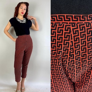 Può includere: Pantaloni a vita alta neri e arancioni con motivo geometrico. I pantaloni sono cropped e hanno una vestibilità slim.