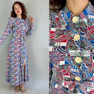 Puede incluir: Un vestido largo blanco con un estampado paisley azul, rojo y verde. El vestido tiene un frente abotonado y un cinturón.