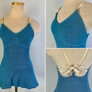 May include: A blue swimsuit with a white criss-cross back strap. The swimsuit has a fitted bodice and a flared skirt.
