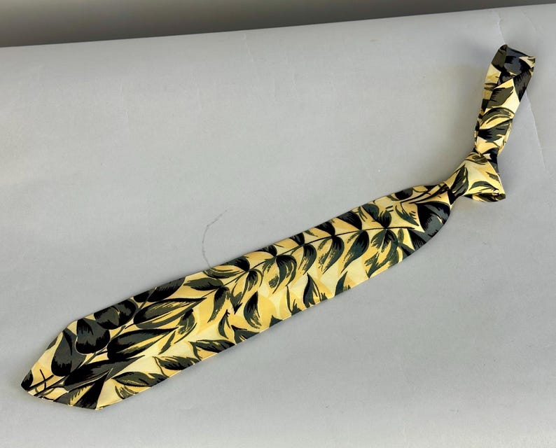 May include: A yellow silk tie with a black leaf pattern.