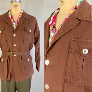 Peut inclure: Une veste marron ceinturée avec un devant boutonné, deux poches à rabat et une seule poche sur le côté gauche. La veste a un col et des manches longues.