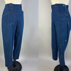 May include: High-waisted dark blue denim pants featuring a side zipper closure, a fitted waistband with belt loops, and angled front pockets with red stitching accents. The pants have a straight-leg cut and are displayed on a mannequin.