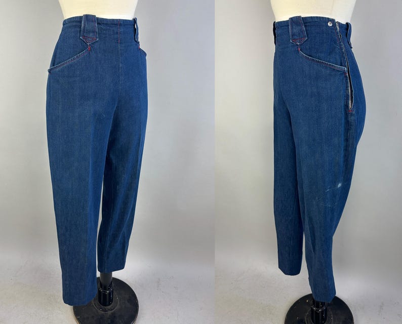 May include: High-waisted dark blue denim pants featuring a side zipper closure, a fitted waistband with belt loops, and angled front pockets with red stitching accents. The pants have a straight-leg cut and are displayed on a mannequin.